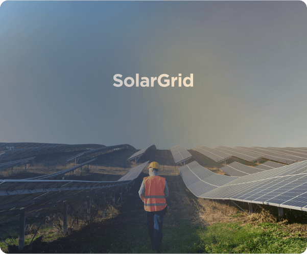 Pessoa usando uniforme de trabalho caminhando, ao lado placas fotovoltaicas de usina elétrica solar.